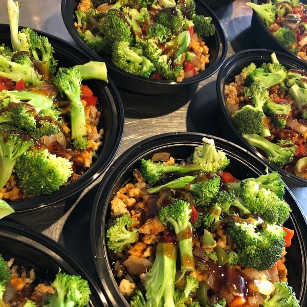 Multiple Roscoes Eatery wraps with broccoli, chicken, and sauce in black containers.