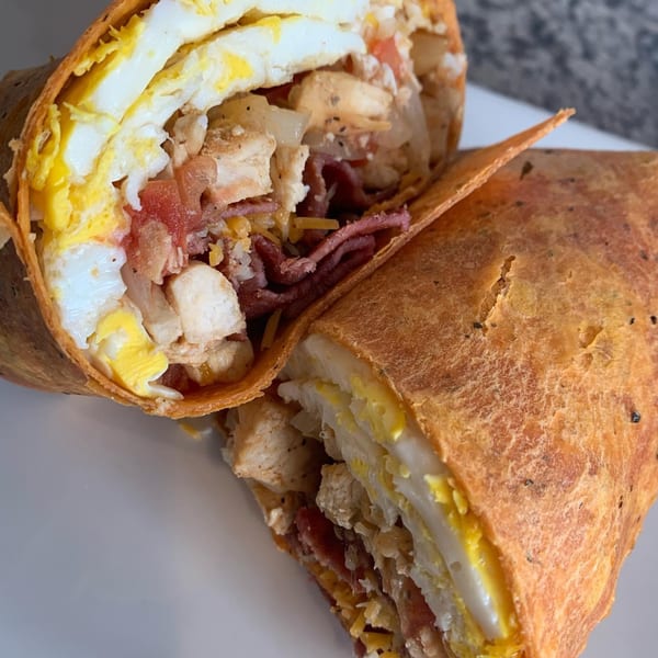 A Roscoes Eatery wrap, cut in half, revealing eggs, chicken, bacon, and cheese.